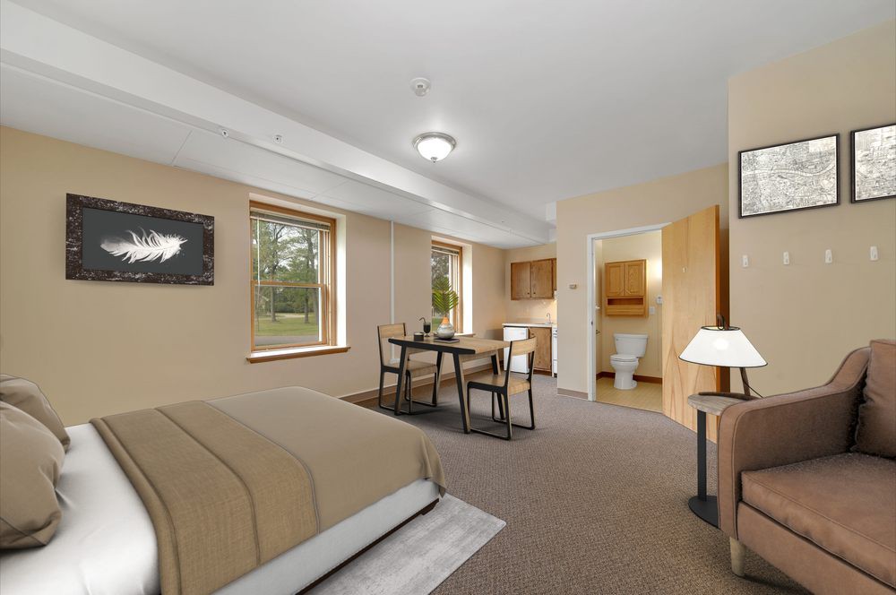 A spacious bedroom with a cozy dining area, featuring modern furniture and neutral tones.