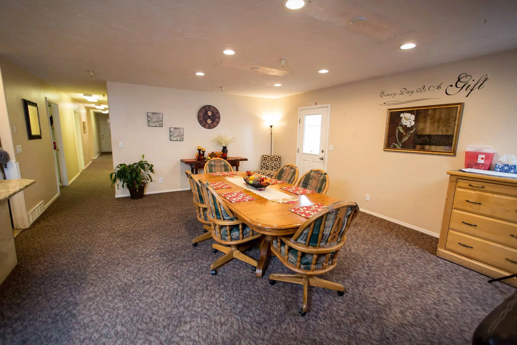 A well-lit conference room with a large wooden table surrounded by cushioned chairs.