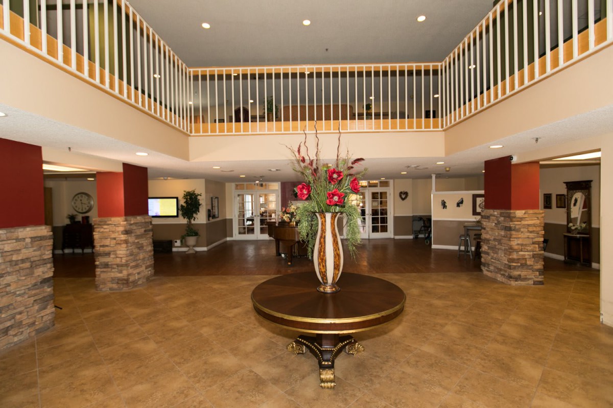 A modern lobby with a round table centerpiece and decorative flowers.