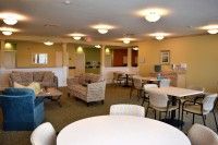 A spacious and well-lit living area featuring sofas, tables, and chairs arranged for comfort.
