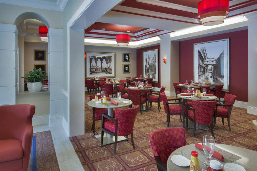 A stylish restaurant interior featuring red-themed decor and neatly arranged tables.