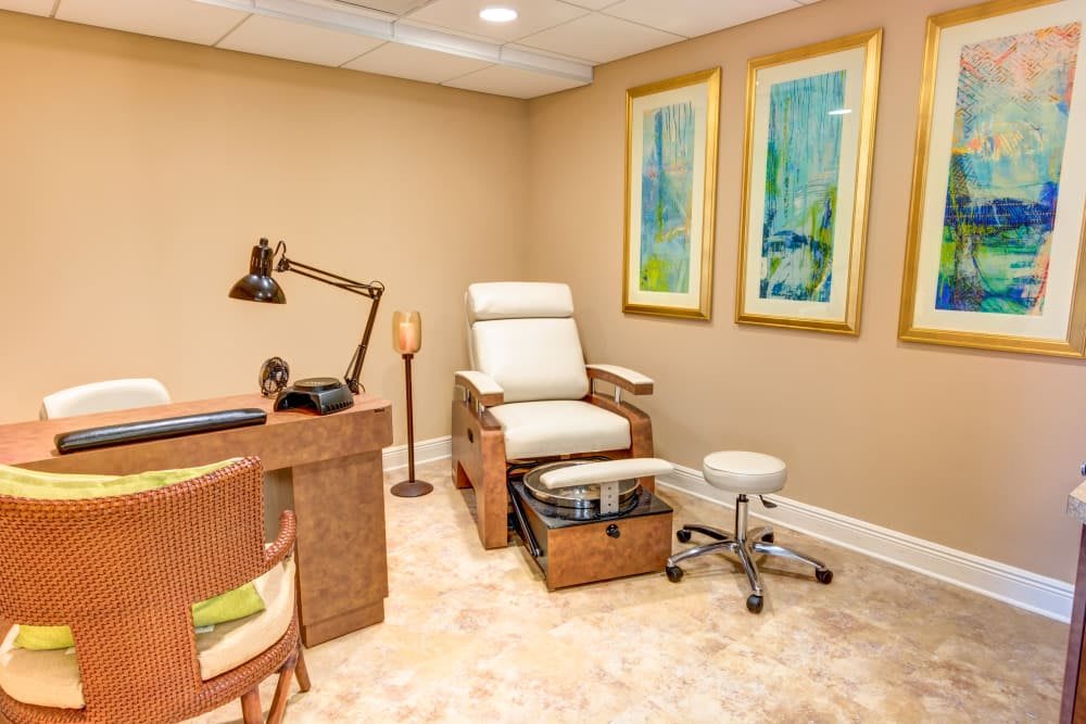 A cozy and well-decorated pedicure area in a spa or nail salon, featuring a comfortable chair and modern artwork.