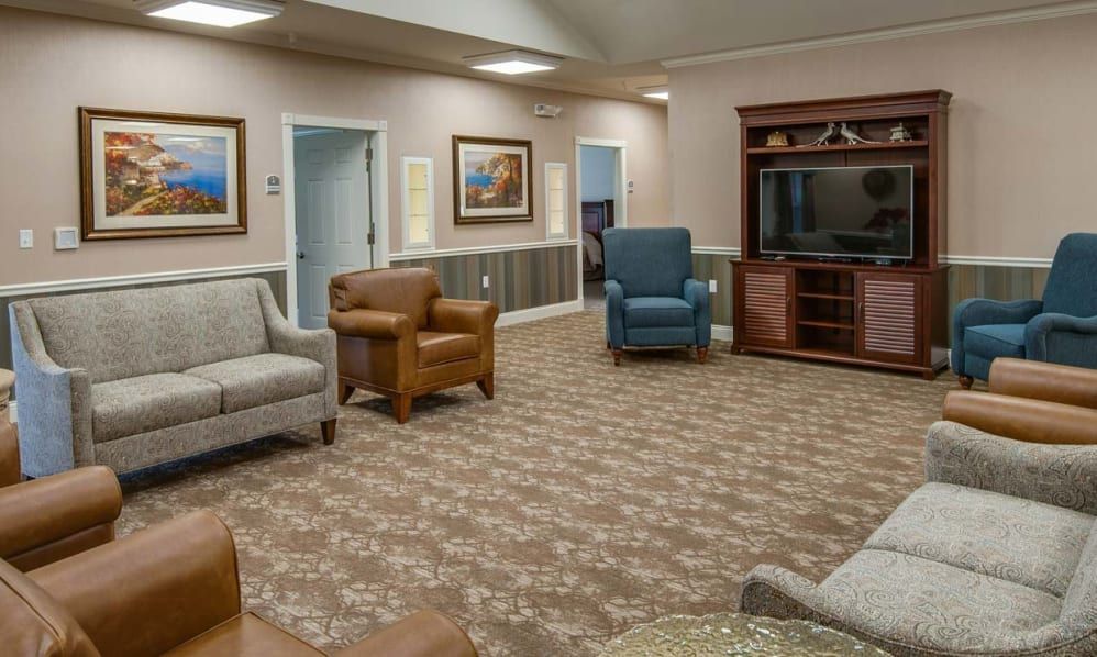 A spacious living room with various seating options and a large television.