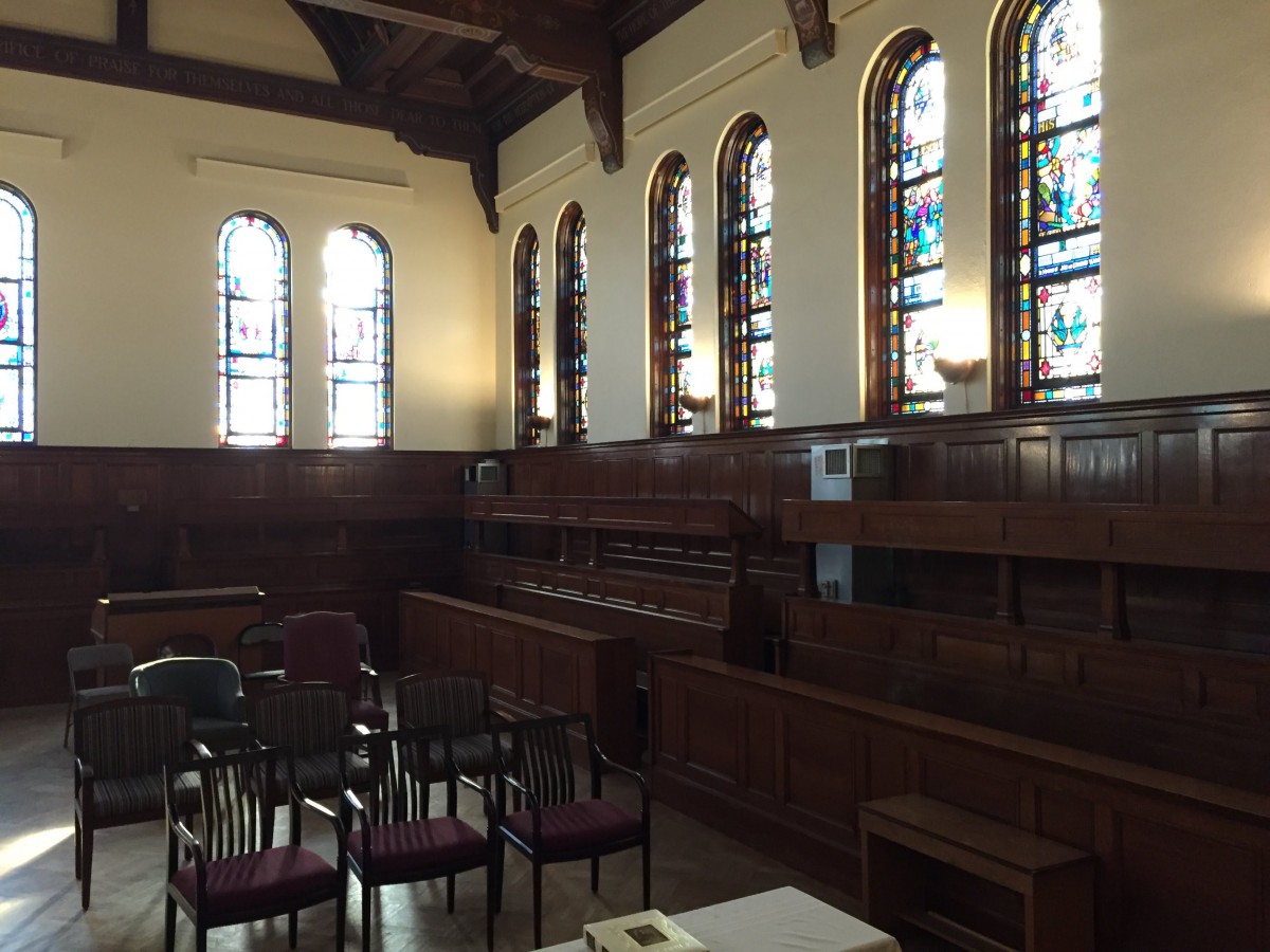 An interior view of a church with stained glass windows and wooden seating.