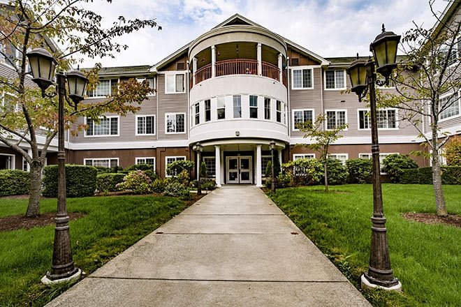 A front view of a residential building with landscaped gardens and a pathway leading to the entrance.