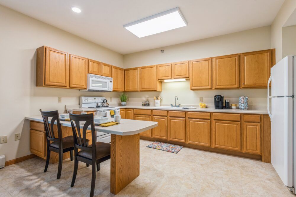 A modern kitchen with wooden cabinets, a small dining table, and various appliances.