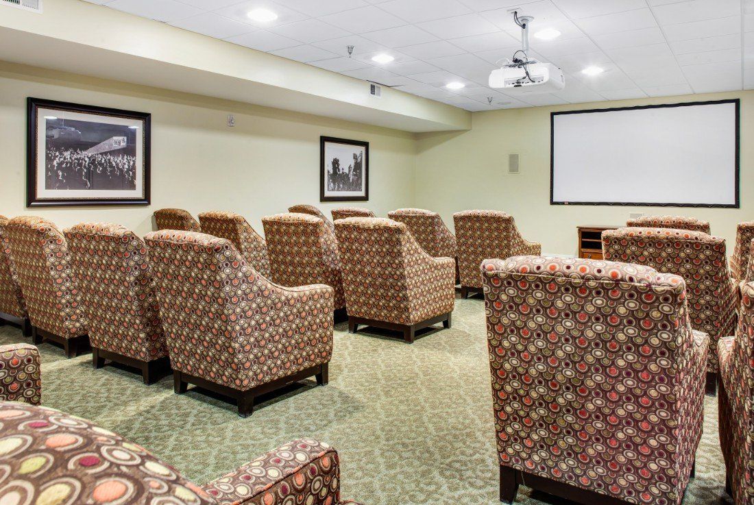 A conference room with patterned chairs facing a projector screen.