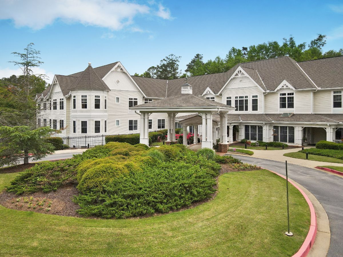 A large, elegant residential building surrounded by well-maintained gardens.