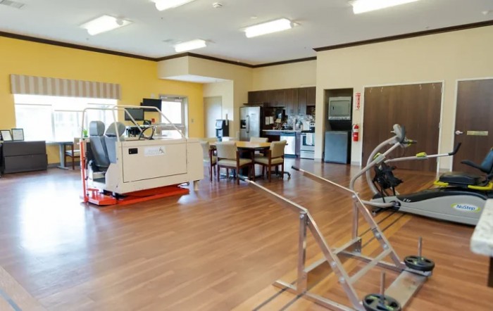 A spacious rehabilitation therapy room equipped with various exercise machines and medical equipment.