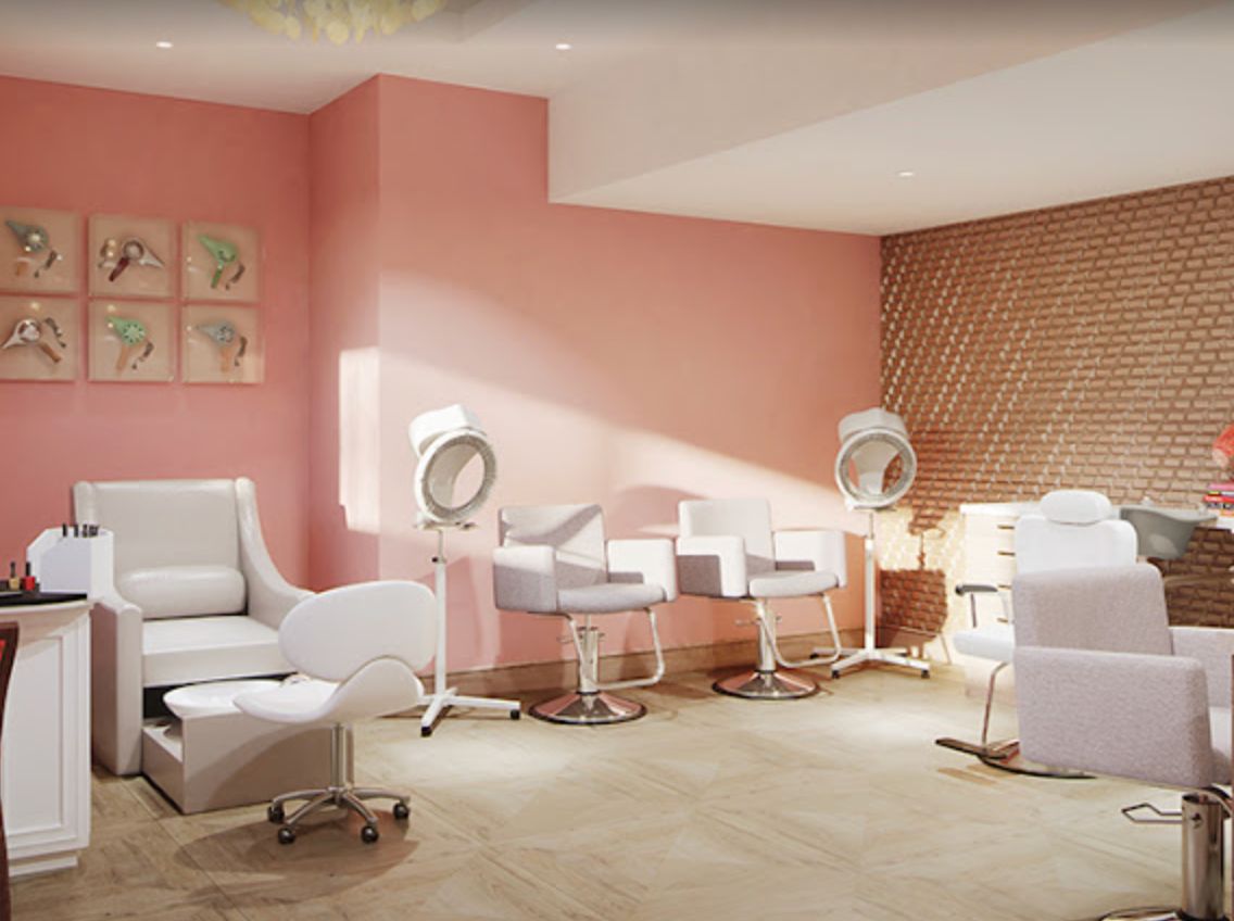 A modern salon interior with pink walls and stylish chairs arranged in front of hairdryers.