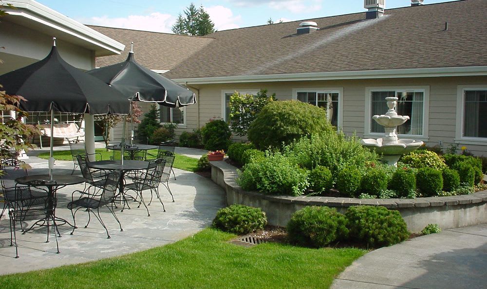 A well-maintained patio area with outdoor seating, surrounded by lush greenery and landscaping.