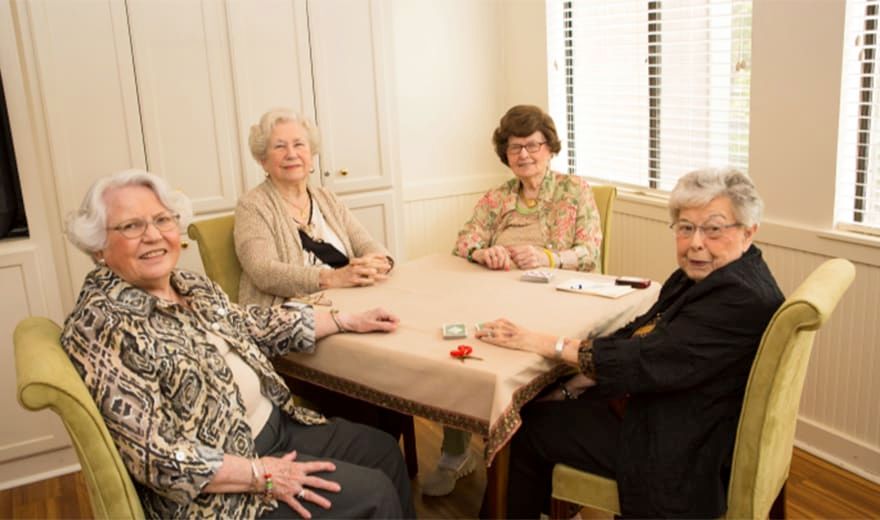 A group of older women sitting around a table having a conversation.