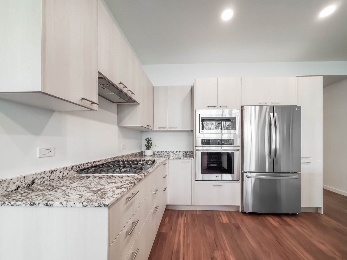 A modern kitchen with stainless steel appliances, granite countertops, and wood flooring.