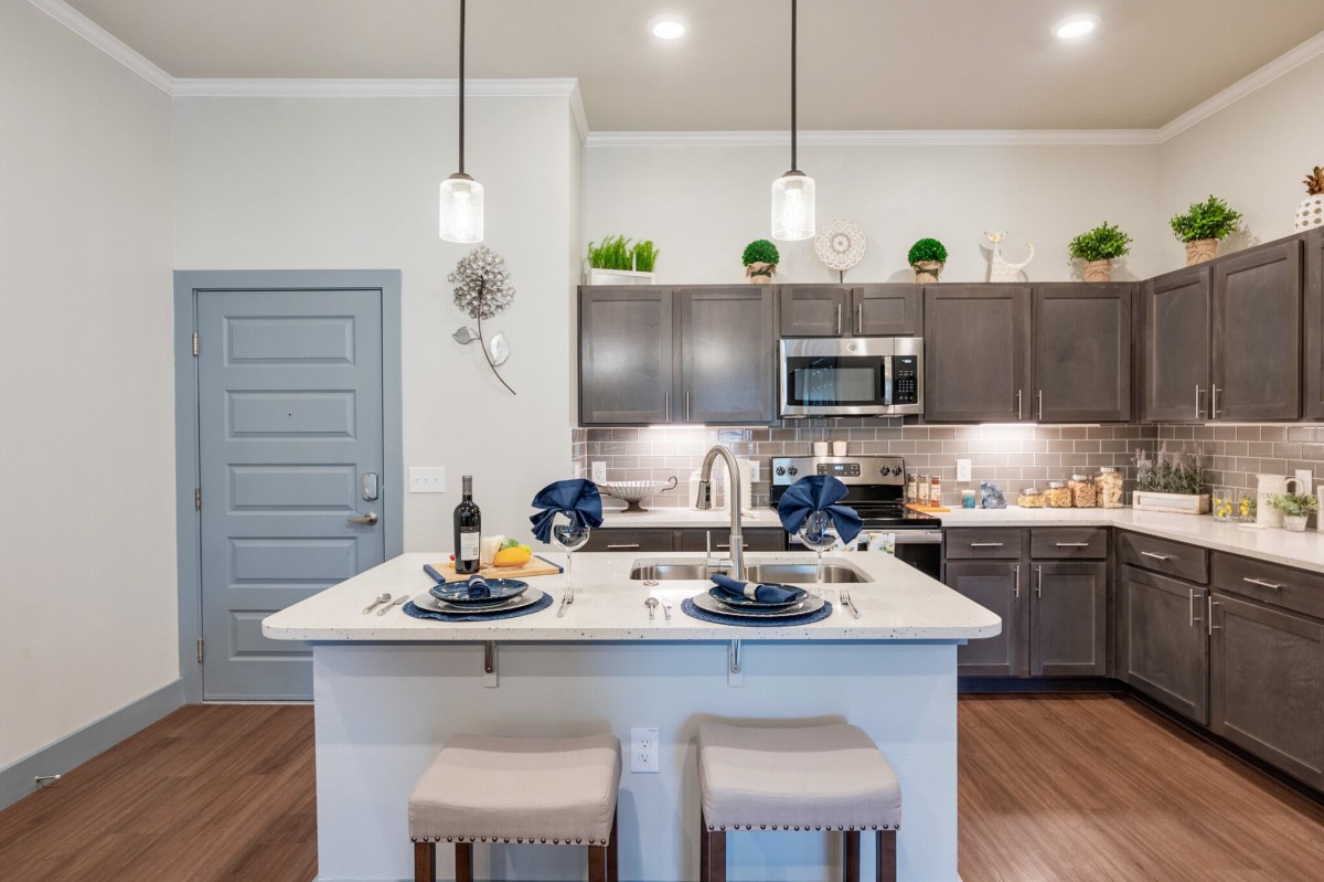 A modern kitchen with an island, pendant lights, and stylish decor.