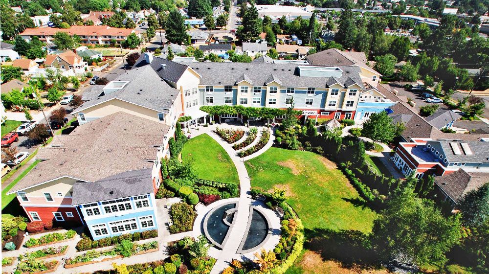 Aerial view of a landscaped garden with a central fountain and surrounding buildings.