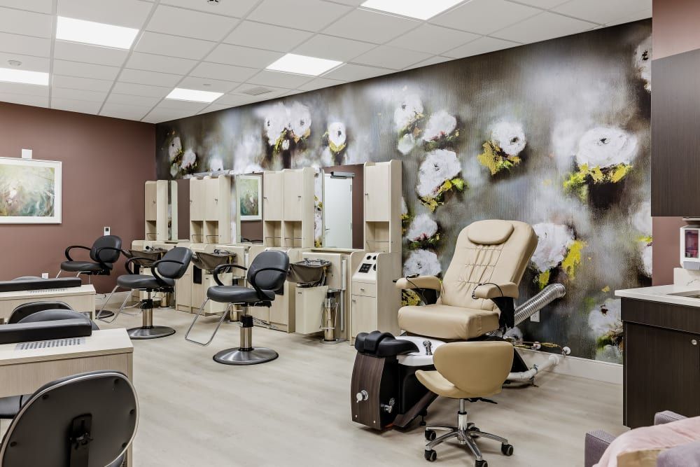 A stylish and modern salon interior with hairdressing stations and floral wallpaper.