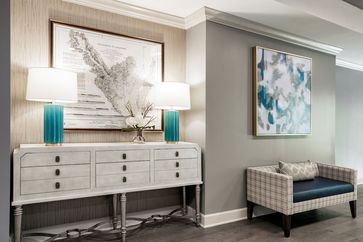 A stylish living room corner featuring a sideboard with modern art pieces, soft lighting from table lamps, and a patterned armchair.