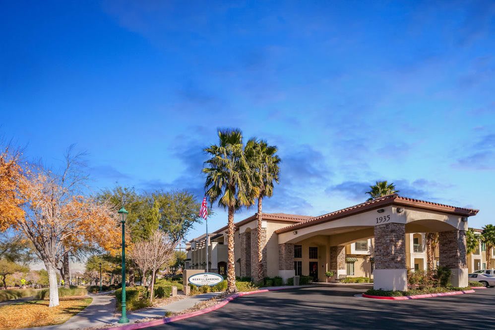 A hotel building surrounded by palm trees under a clear blue sky.