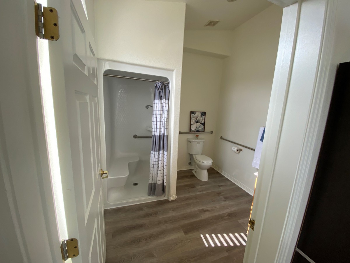A modern, accessible bathroom with a spacious shower and handrails.