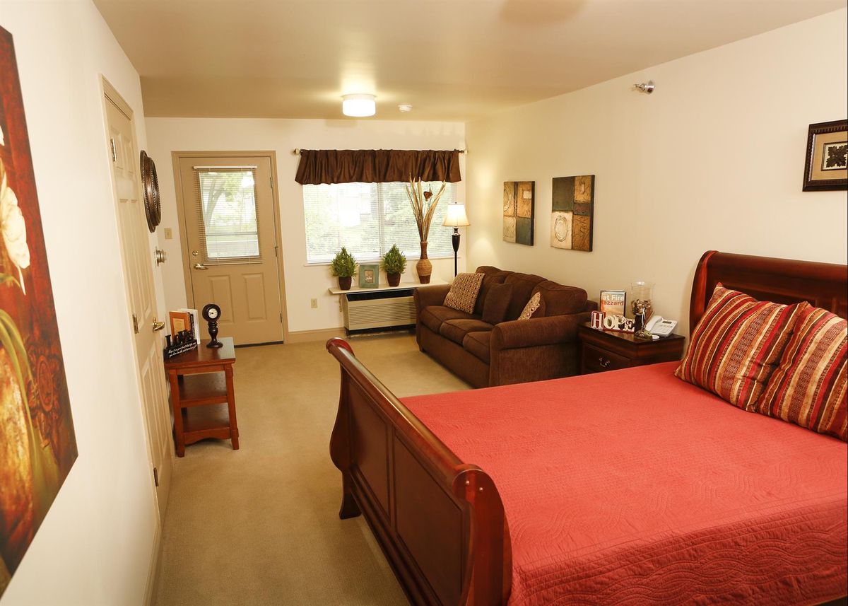 Cozy bedroom with a warm color scheme featuring a bed, sofa, and elegant decor.