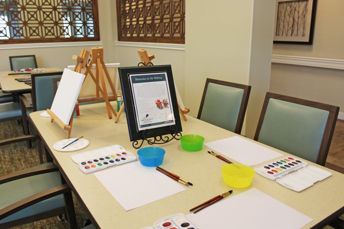 A table set up for an art class with easels, paint palettes, brushes, and paper.
