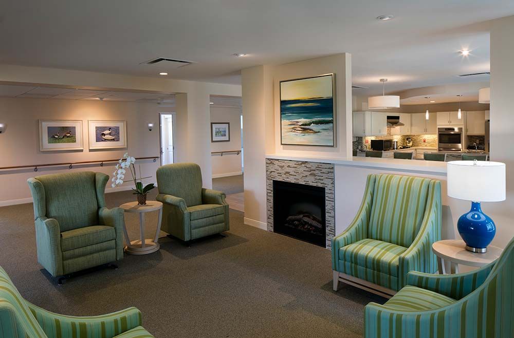 A cozy living room with green armchairs and a fireplace, featuring modern artwork on the walls.