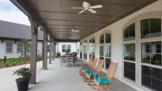 A covered porch with rocking chairs and a ceiling fan, offering a cozy outdoor seating area.