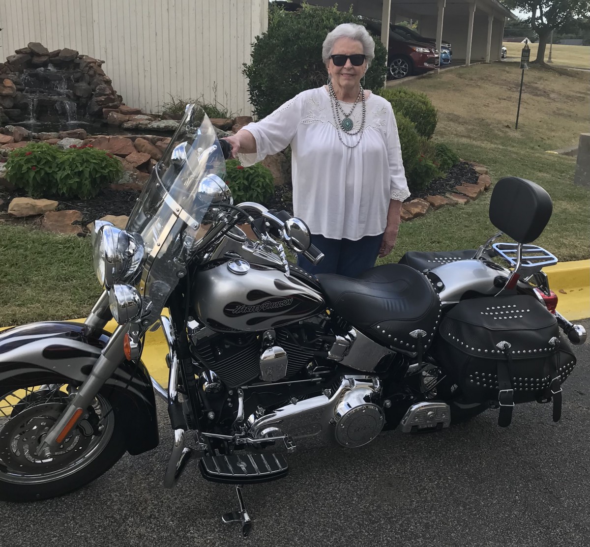 A woman standing next to a motorcycle outdoors.