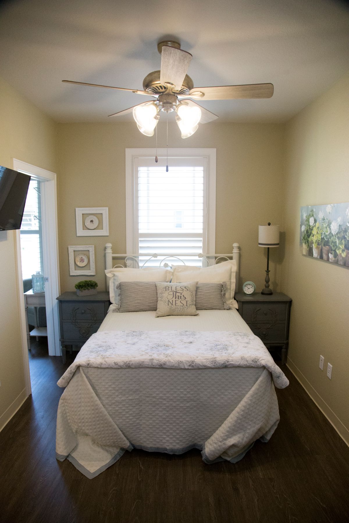 A cozy bedroom with a neatly made bed, wall-mounted TV, and elegant decor.