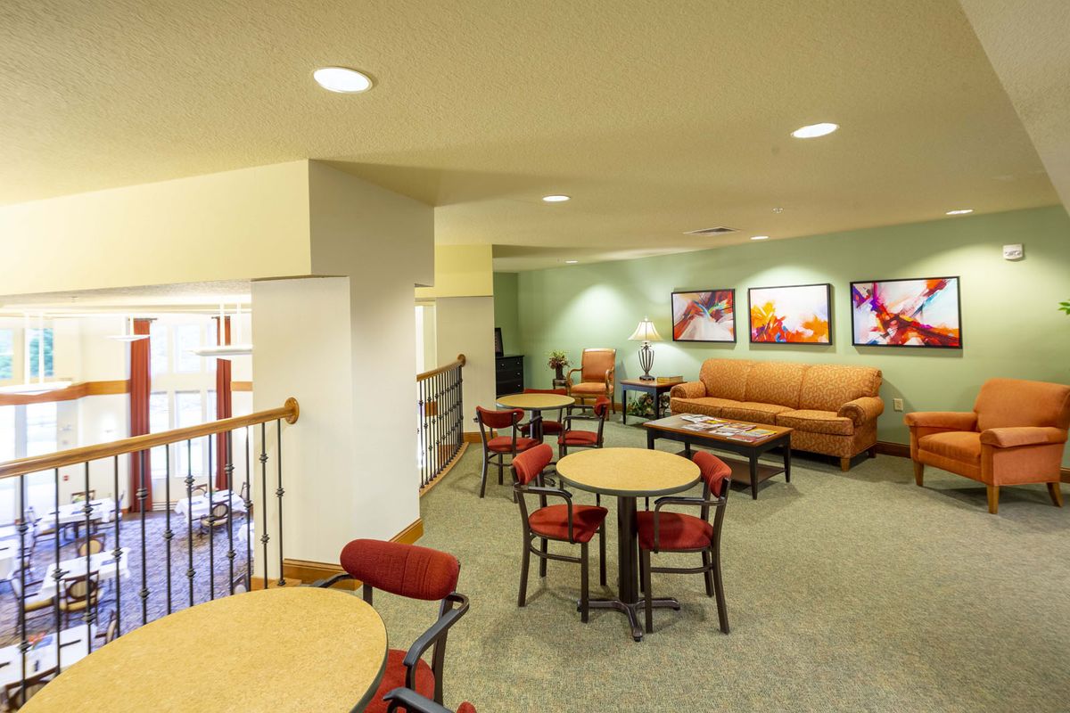 A comfortable lounge area with tables, chairs, and a sofa, decorated with artwork on the walls.