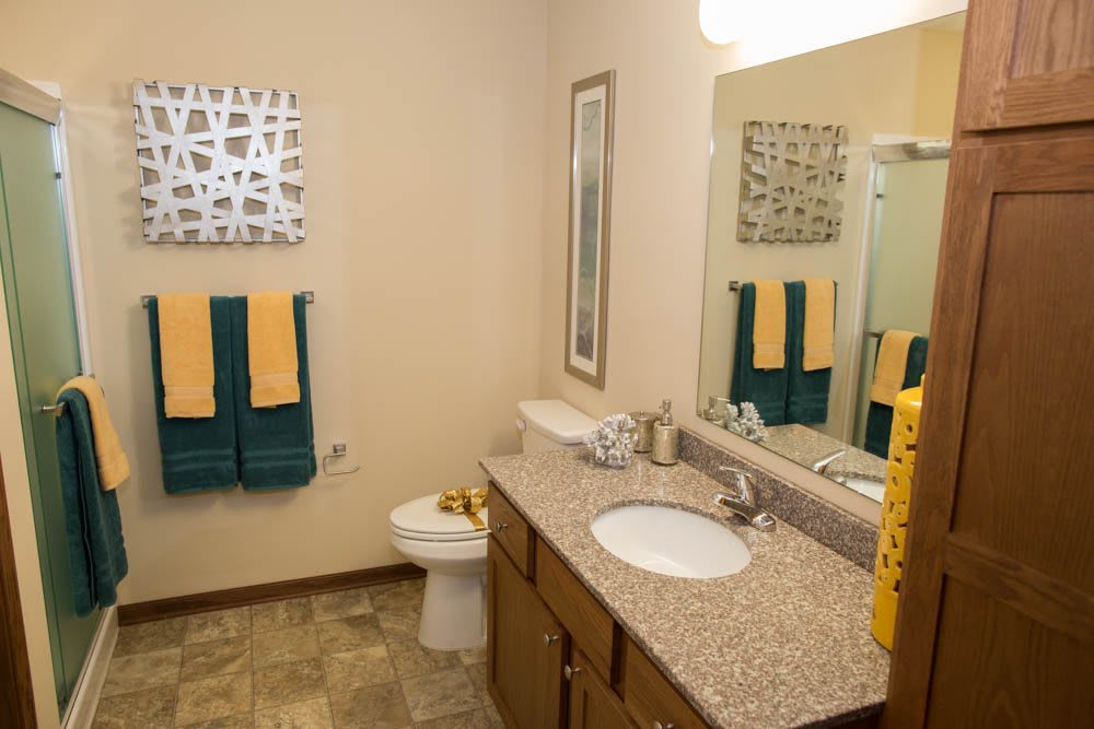 A modern bathroom interior with a double sink, mirror, and colorful towels.