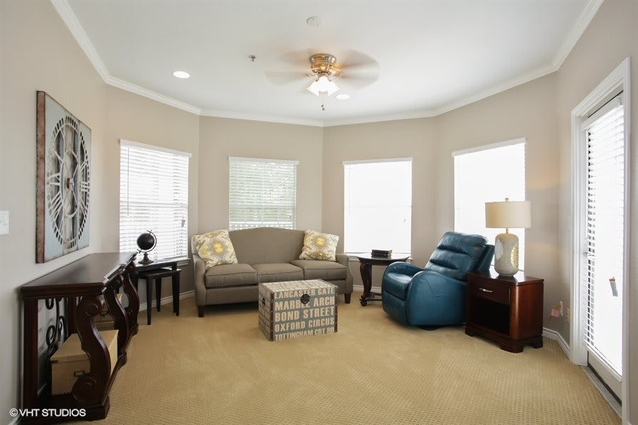 A cozy living room with a sofa, recliner, and multiple windows letting in natural light.