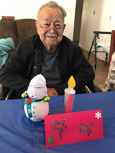 An elderly man smiles warmly beside festive decorations, embodying the joy of the holiday spirit.