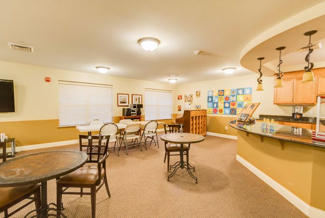 A cozy dining area with round tables and chairs, decorated with artwork on the walls.