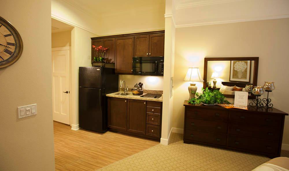A modern kitchenette area with wooden cabinets, a refrigerator, and a microwave.