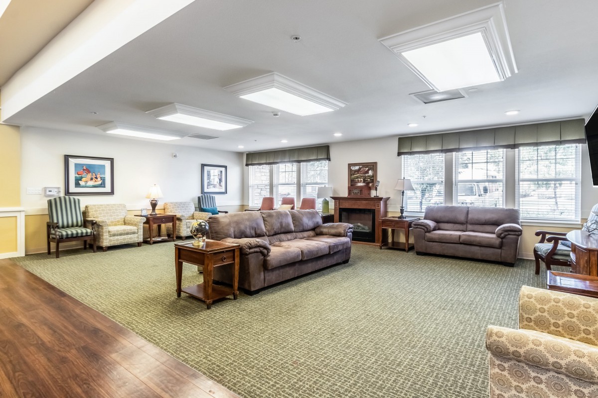 A spacious living room with multiple sofas and natural light from large windows.