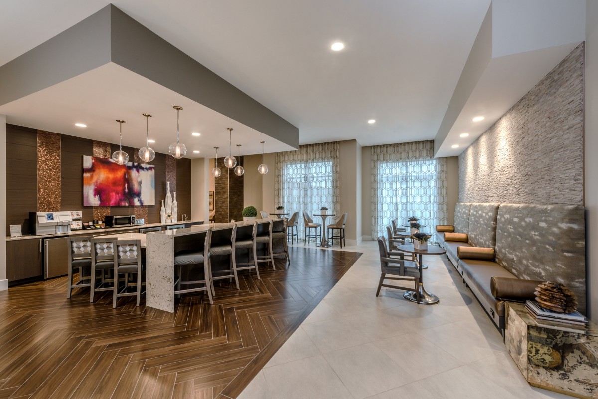A modern kitchen and dining area featuring a bar with stools and elegant pendant lighting.