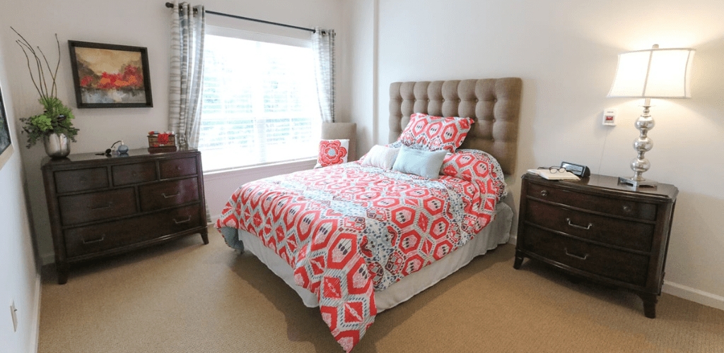 A cozy bedroom with a colorful geometric patterned bedspread and ample natural light.