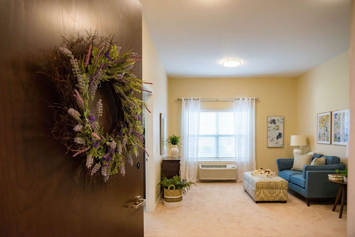 A cozy living room with a wreath on the door, featuring comfortable furniture and soft lighting.