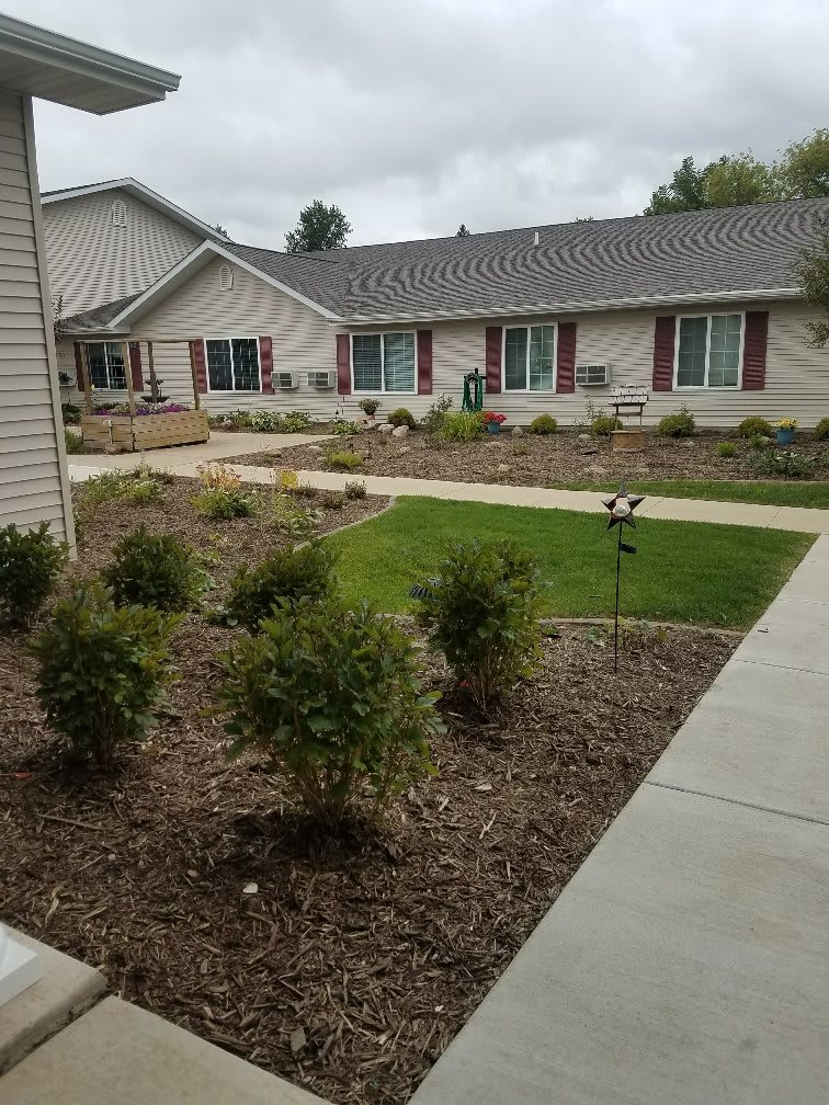 A landscaped garden area with bushes and pathways outside a residential building.