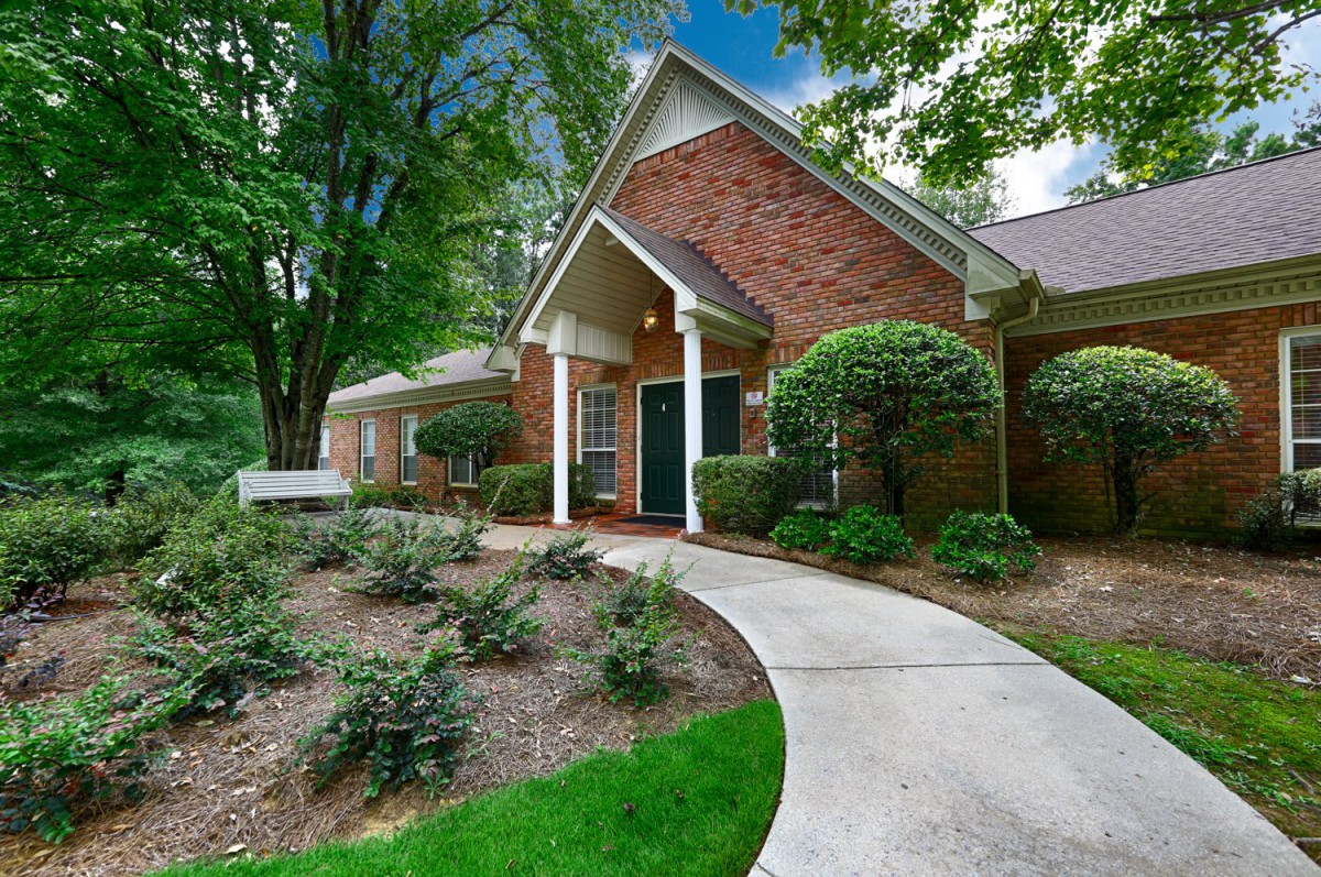 A charming brick house with a landscaped garden and a curved pathway leading to the entrance.