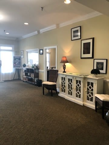 A warmly decorated lobby with chairs, a cabinet, and framed artwork on the walls.