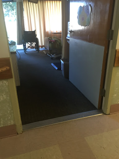 A view of an open door leading into a hospital room, with a wheelchair visible in the background.