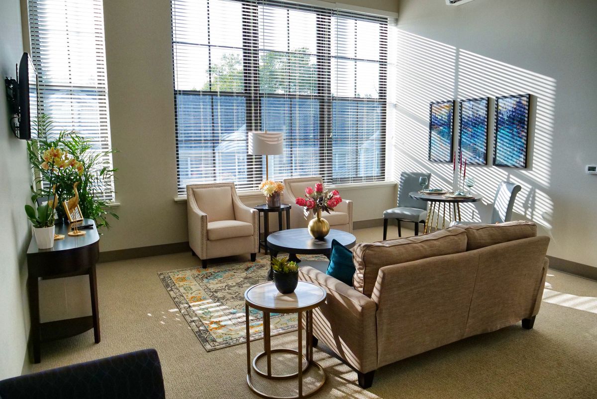 A modern living room with large windows allowing natural light, featuring comfortable furniture and stylish decor.