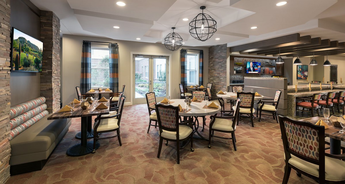 An elegantly designed dining room with multiple tables and chairs, featuring modern chandeliers and a cozy atmosphere.