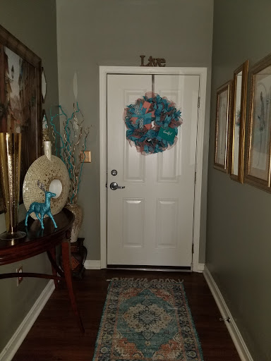 A cozy entrance featuring a vibrant wreath and artistic wall decorations.
