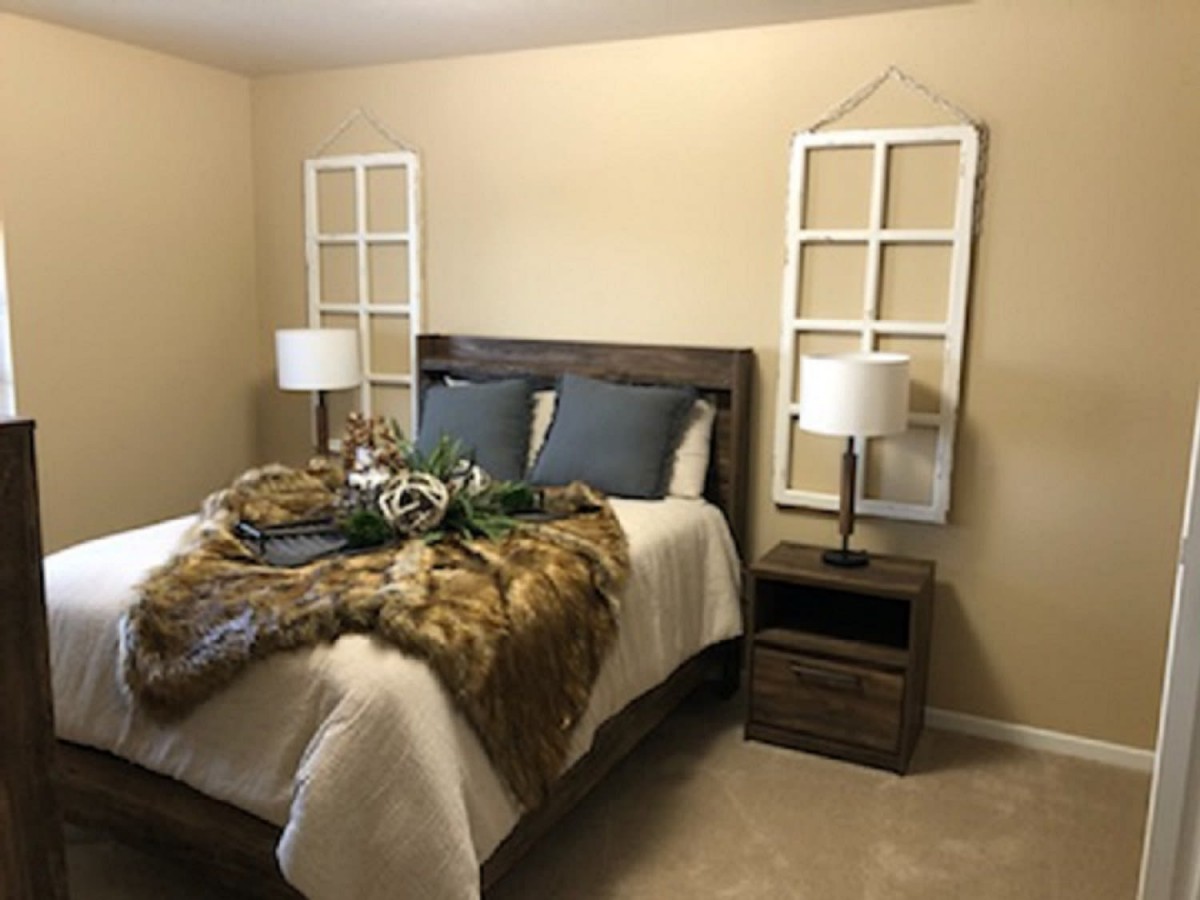 A cozy bedroom interior with a neatly made bed, accented by two lamps and decorative items.