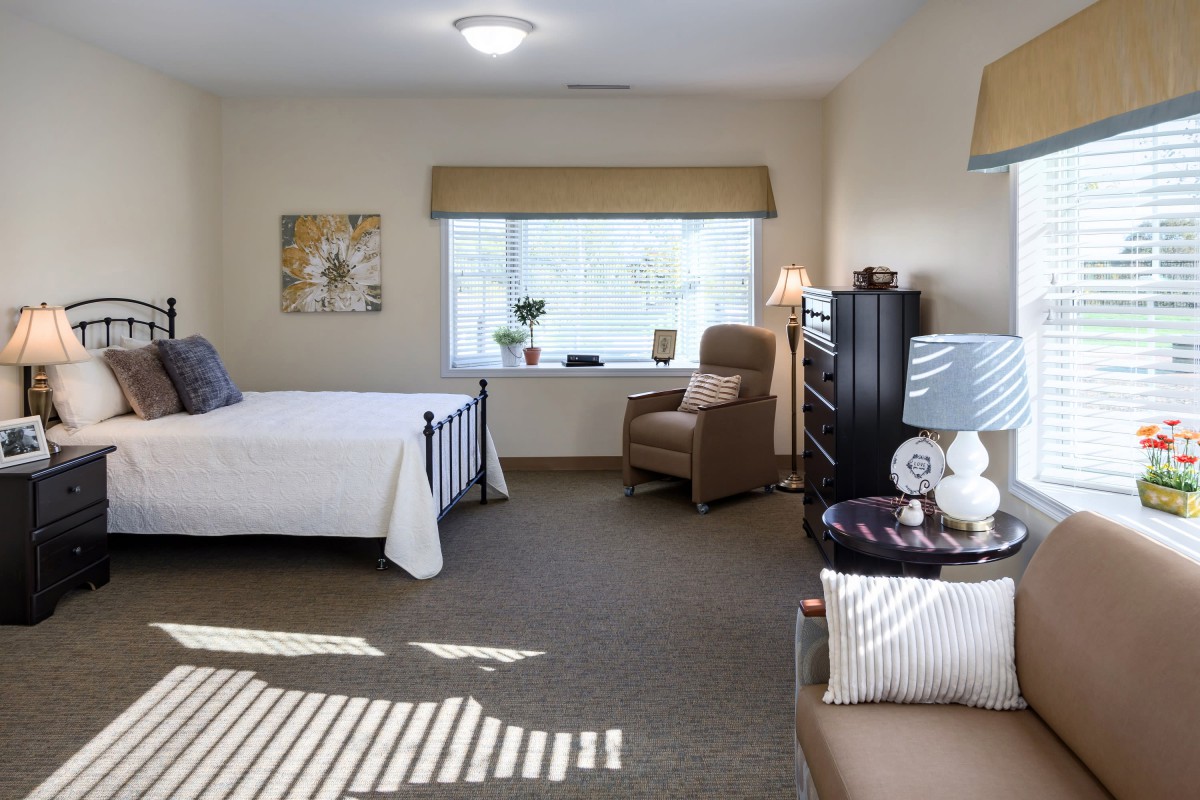 A cozy bedroom with a bed, armchair, and decorative elements.