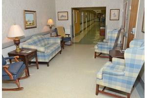 A cozy lounge area with plaid sofas and chairs near a hallway.
