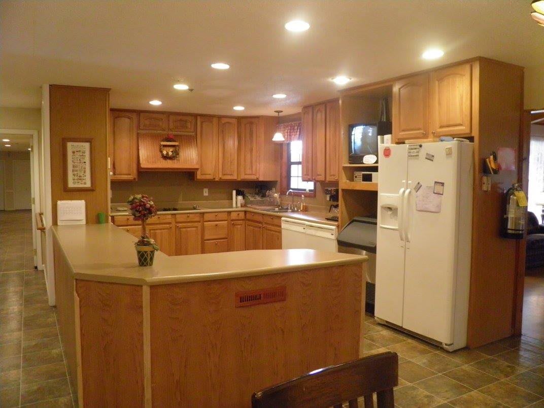 A spacious kitchen with wooden cabinets, a large countertop island, and a refrigerator.